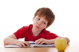 boy studying and distracted with an apple