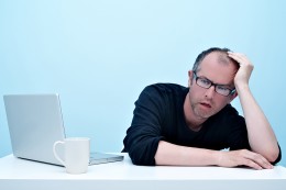 Man at desk leaning his head on his hand